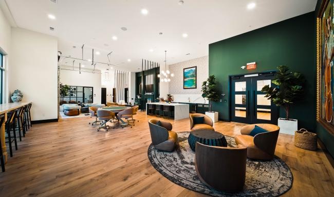 Cutting-edge amenities at your fingertips a clubhouse room with chairs, tables and wood floors